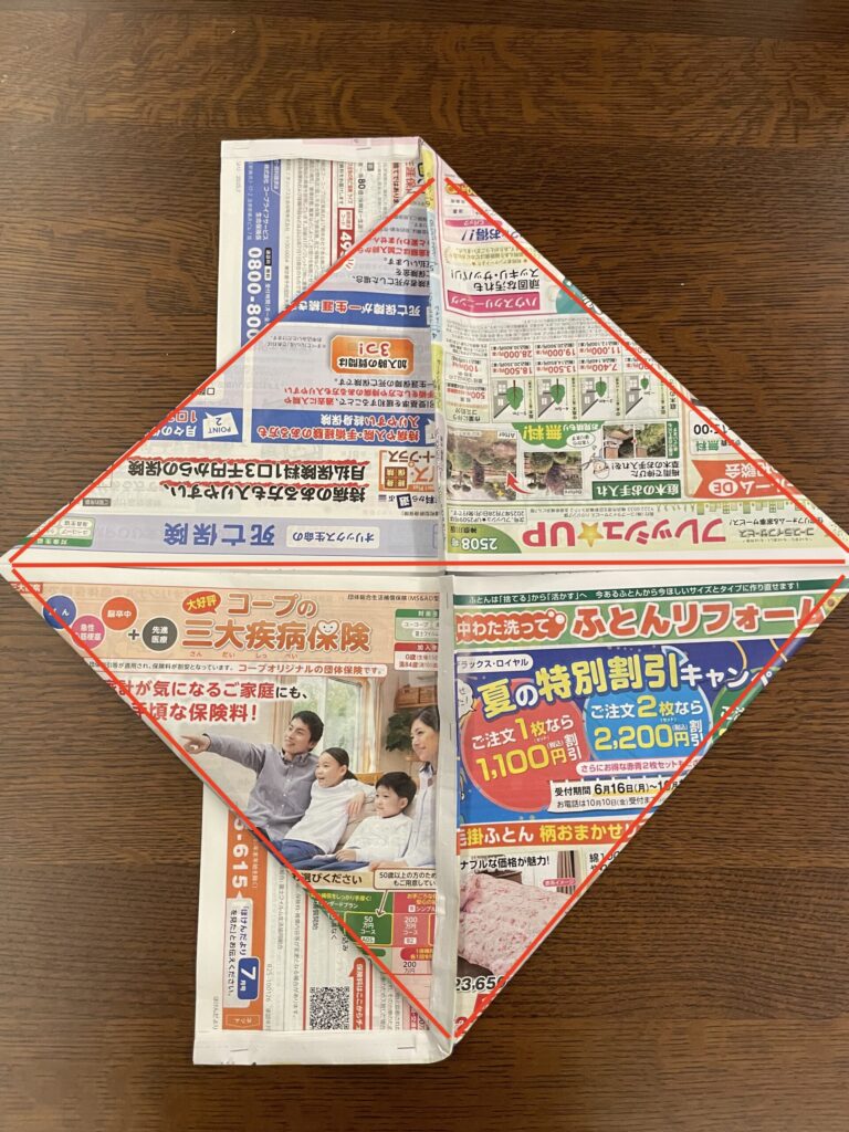 折り曲げた部分の袋になっているところを広げ、つぶすように上下三角形に折った様子