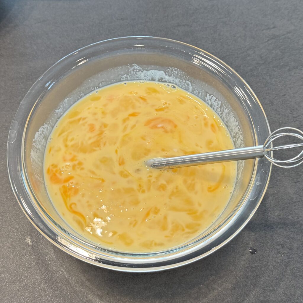 溶いた卵と加熱した牛乳を混ぜてプリン液を作成している様子