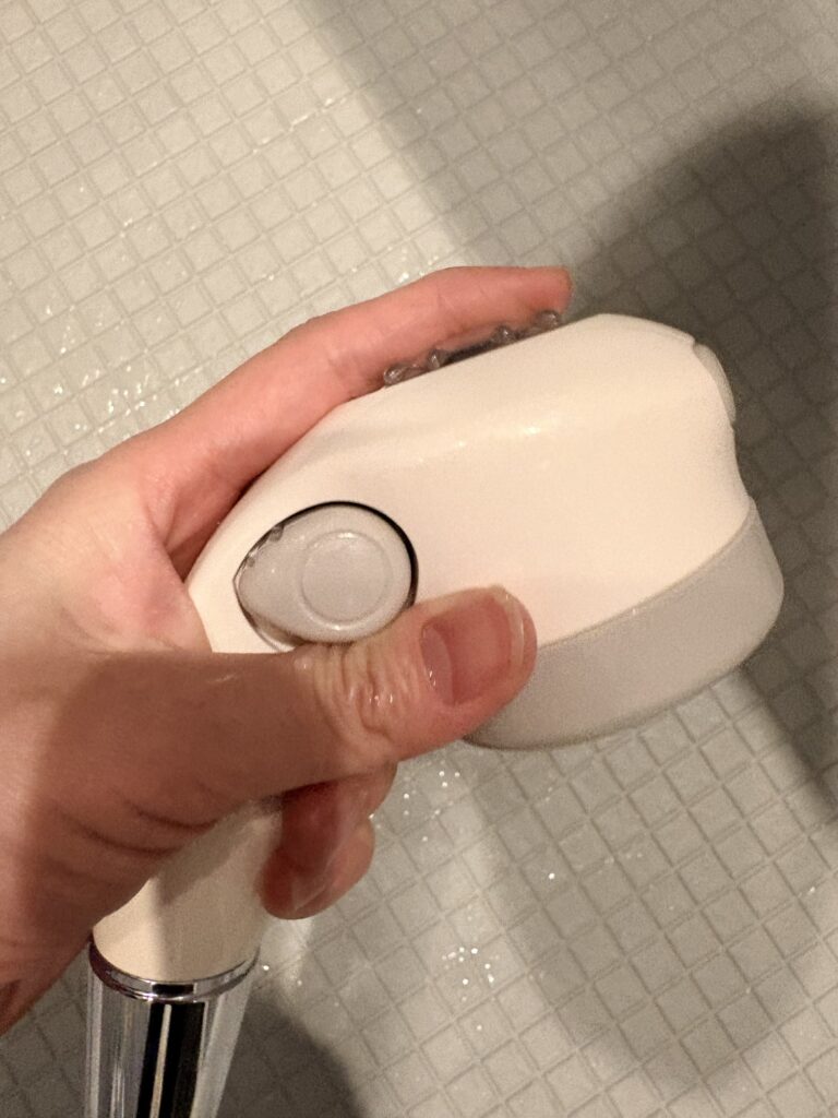 赤ちゃん用のコンパクトシャワーヘッドを片手で持っている様子