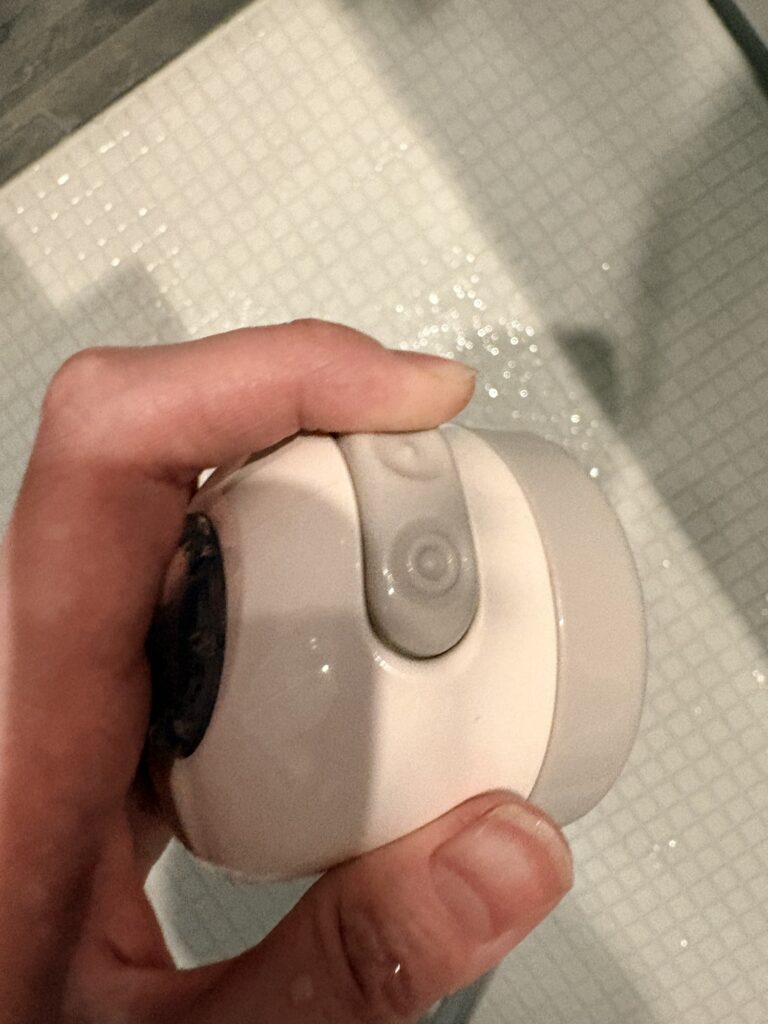 赤ちゃん用シャワーヘッドの手元ボタンでスポットとワイドを切り替えている様子